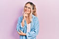 Beautiful young blonde woman wearing casual clothes and glasses looking confident at the camera with smile with crossed arms and Royalty Free Stock Photo