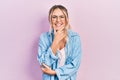 Beautiful young blonde woman wearing casual clothes and glasses looking confident at the camera smiling with crossed arms and hand Royalty Free Stock Photo