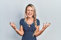 Beautiful young blonde woman wearing casual striped dress crazy and mad shouting and yelling with aggressive expression and arms Royalty Free Stock Photo