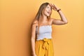 Beautiful young blonde woman wearing casual summer clothes very happy and smiling looking far away with hand over head Royalty Free Stock Photo