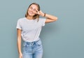 Beautiful young blonde woman wearing casual white t shirt doing peace symbol with fingers over face, smiling cheerful showing Royalty Free Stock Photo