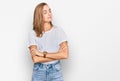 Beautiful young blonde woman wearing casual white t shirt looking to the side with arms crossed convinced and confident Royalty Free Stock Photo