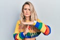 Beautiful young blonde woman wearing colored sweater doing time out gesture with hands, frustrated and serious face Royalty Free Stock Photo