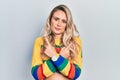 Beautiful young blonde woman wearing colored sweater pointing to both sides with fingers, different direction disagree Royalty Free Stock Photo