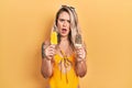 Beautiful young blonde woman wearing summer swimsuit holding ice creams in shock face, looking skeptical and sarcastic, surprised Royalty Free Stock Photo