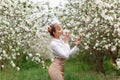 Beautiful young blonde woman in white shirt posing under apple tree in blossom in Spring garden Royalty Free Stock Photo