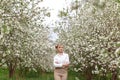 Beautiful young blonde woman in white shirt posing under apple tree in blossom in Spring garden Royalty Free Stock Photo