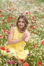 a beautiful young blonde woman in a yellow dress stands among a flowering field Royalty Free Stock Photo