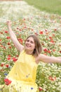 a beautiful young blonde woman in a yellow dress stands among a flowering field Royalty Free Stock Photo