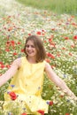 a beautiful young blonde woman in a yellow dress stands among a flowering field Royalty Free Stock Photo