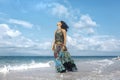 Beautiful young boho woman walking by the shore line through the Royalty Free Stock Photo