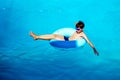 Beautiful young boy with inflatable ring relaxing in blue swimming pool Royalty Free Stock Photo