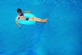 Beautiful young boy with inflatable ring relaxing in blue swimming pool Royalty Free Stock Photo