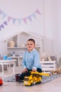 young boy playing toy trucks sitting on the floor in the children`s room Royalty Free Stock Photo