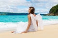 Beautiful young bride with angel wings on the sea coast. Tropical sea in the background.