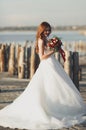 Beautiful young bride with bridal bouquet posing on the background sea Royalty Free Stock Photo