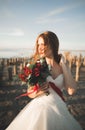 Beautiful young bride with bridal bouquet posing on the background sea Royalty Free Stock Photo