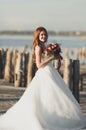 Beautiful young bride with bridal bouquet posing on the background sea Royalty Free Stock Photo