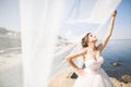 Beautiful young bride with bridal bouquet posing on the background sea Royalty Free Stock Photo