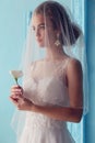 Beautiful young bride with dark curly hair in luxurious wedding dress posing at room Royalty Free Stock Photo