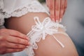 Beautiful young bride hands with a manicure hold a white garter Royalty Free Stock Photo