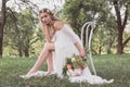 beautiful young bride holding wedding bouquet and looking at camera while sitting on chair Royalty Free Stock Photo