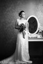 Beautiful young bride holding wedding bouquet near mirror Royalty Free Stock Photo