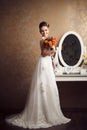 Beautiful young bride holding wedding bouquet near mirror Royalty Free Stock Photo