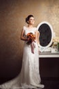 Beautiful young bride holding wedding bouquet near mirror Royalty Free Stock Photo