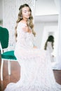 Beautiful young bride with long blond curly hair in a long white lacy dressing gown in the morning Royalty Free Stock Photo