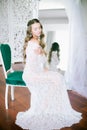 Beautiful young bride with long blond curly hair in a long white lacy dressing gown in the morning Royalty Free Stock Photo