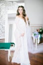 Beautiful young bride with long blond curly hair in a long white lacy dressing gown in the morning Royalty Free Stock Photo