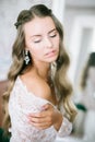 Beautiful young bride with long blond curly hair in a long white lacy dressing gown in the morning Royalty Free Stock Photo