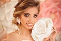 Beautiful young bride with makeup and fashion wedding hairstyle. Closeup portrait of young gorgeous woman over roses flowers. Royalty Free Stock Photo