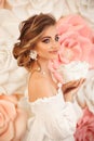 Beautiful young bride with makeup and fashion wedding hairstyle. Closeup portrait of young gorgeous woman over roses flowers. Royalty Free Stock Photo