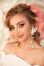 Beautiful young bride with makeup and fashion wedding hairstyle. Closeup portrait of young gorgeous woman over roses flowers. Royalty Free Stock Photo