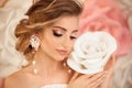 Beautiful young bride with makeup and fashion wedding hairstyle. Closeup portrait of young gorgeous woman over roses flowers. Royalty Free Stock Photo