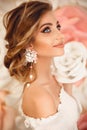 Beautiful young bride with makeup and fashion wedding hairstyle. Closeup portrait of young gorgeous woman over roses flowers. Royalty Free Stock Photo