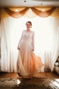 Beautiful young bride near the window in full growth Royalty Free Stock Photo