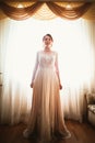 Beautiful young bride near the window in full growth Royalty Free Stock Photo