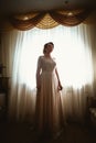 Beautiful young bride near the window in full growth Royalty Free Stock Photo