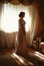 Beautiful young bride near the window in full growth Royalty Free Stock Photo