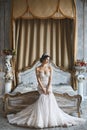 Beautiful young bride, brunette model girl in the stylish and fashionable wedding dress with naked shoulders sits Royalty Free Stock Photo