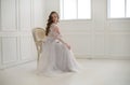 Beautiful young bride sitting on a chair in white room. Royalty Free Stock Photo