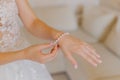 Beautiful young bride straightens her bracelet on her hand on a wedding day.