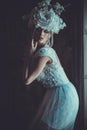 Beautiful young bride wearing white dress and wreath of flowers sits on a chair. Luxury palace. Royalty Free Stock Photo