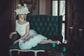 Beautiful young bride wearing white dress and wreath of flowers sits on a chair. Luxury palace. Royalty Free Stock Photo