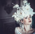 Beautiful young bride wearing white dress and wreath of flowers sits on a chair. Luxury palace. Royalty Free Stock Photo