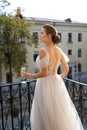 A beautiful young bride in a wedding dress is standing on the balcony, drinking and smiling. Royalty Free Stock Photo