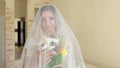Portrait of bride with flowers and a veil at home.